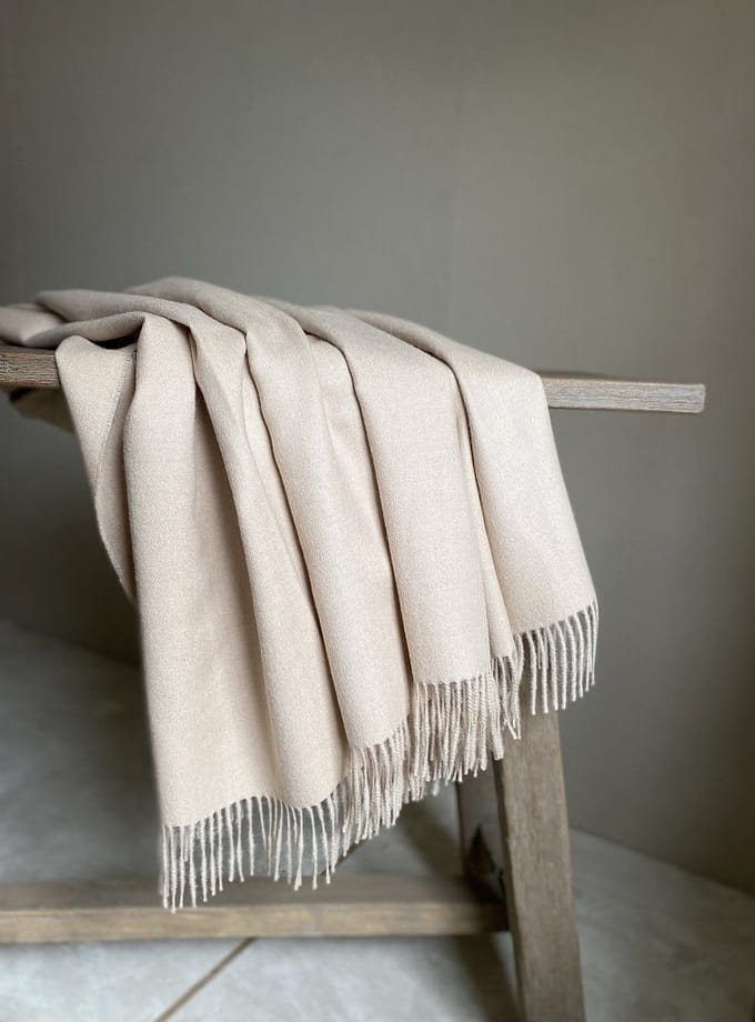 pläd i baby alpacka draperad över en bänk|pläd i babyalpacka ihopvikt på en rustik bänk