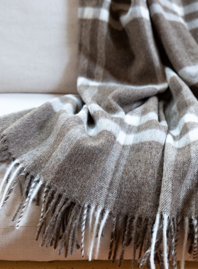 merinoull pläd i brunt hängande på en fåtölj