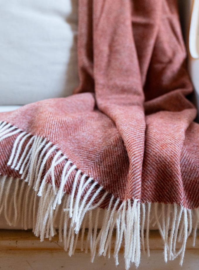 ullpläd i terrakotta hängandes på en fåtölj