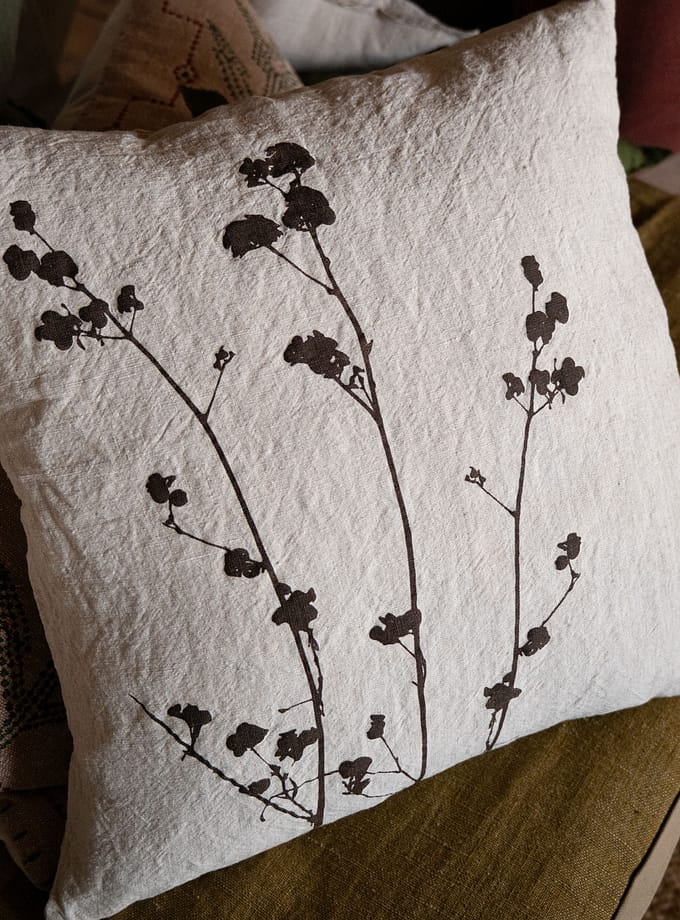 närbild på linnekudde med botaniskt mönster i chokladbrunt