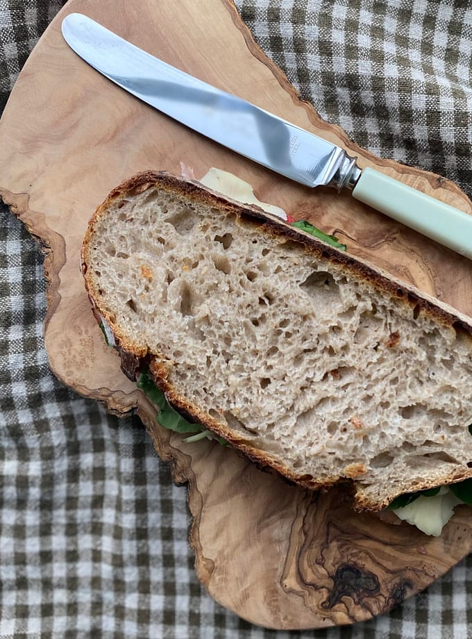 en smörgås och ett kniv liggande på en bräda i olivträ