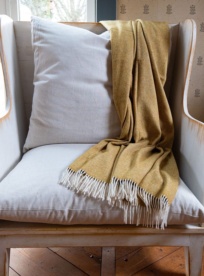 pläd i gul merinoa upp liggande på en fåtölj