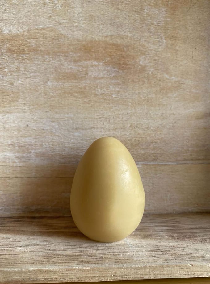 gul, äggformad bixax balm mot en bakgrund i trä
